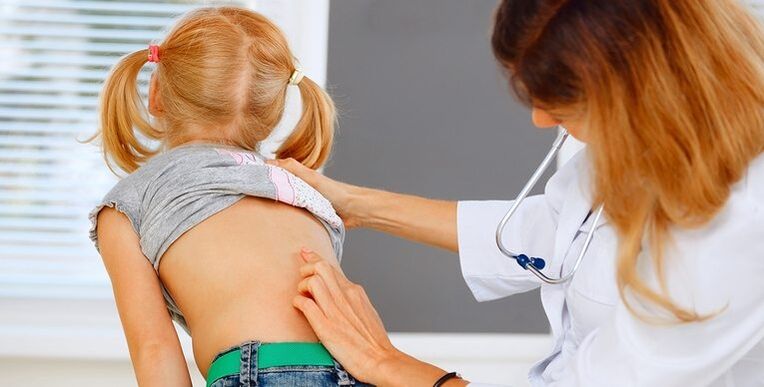 medico che esamina la schiena di un bambino per il mal di schiena